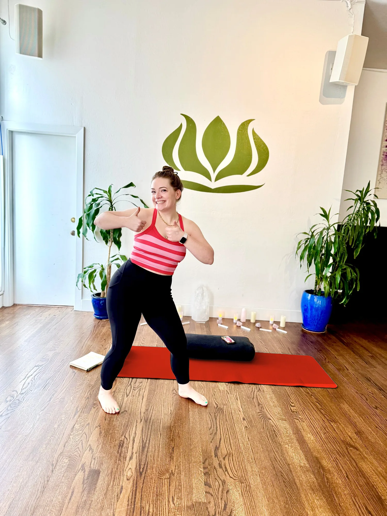 Sara standing in a yoga studio beside an orange yoga mat