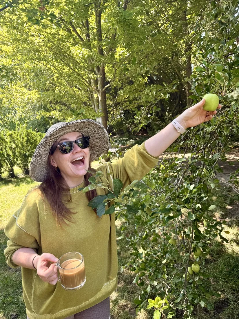 Sara smiling while picking an apple outdoors